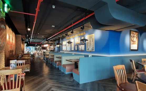Proyecto Emo entrada de restaurante iluminado con pared azul y suelo de madera