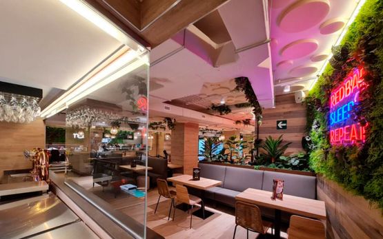 Proyecto Emo mesas de restaurante y sillas con techo y pred de neon y cesped moderno